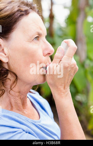 Woman using asthma inhaler Stock Photo