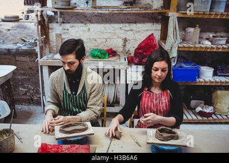 Male potter with female colleague working at table Stock Photo