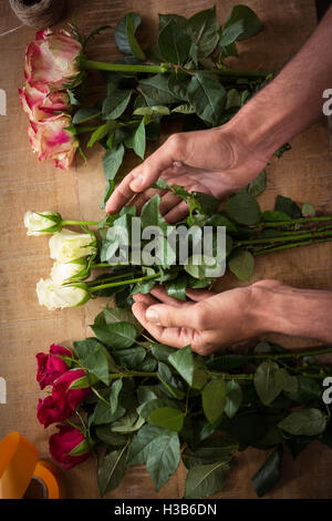 Male florist arranging flowers on the wooden worktop Stock Photo