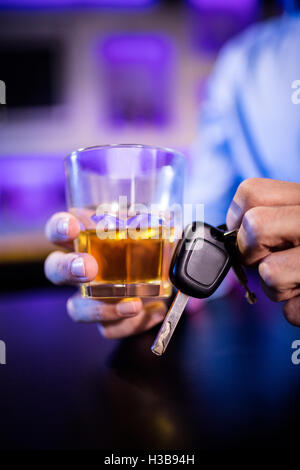 Man holding a glass of whiskey and car keys