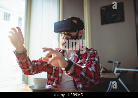 Hipster using virtual reality headset at cafeteria Stock Photo