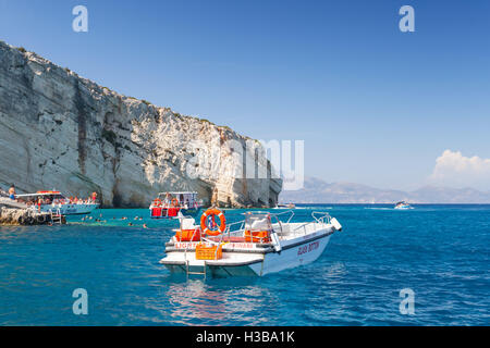 Zakynthos, Greece - August 20, 2016: White pleasure motor boat floating on sea water near rocky island coast in summer day Stock Photo