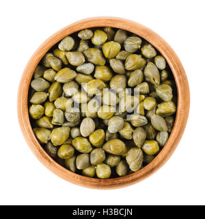 Capers in wooden bowl on white background. Edible flower buds of Capparis spinosa, caper bush or Flinders rose. Stock Photo