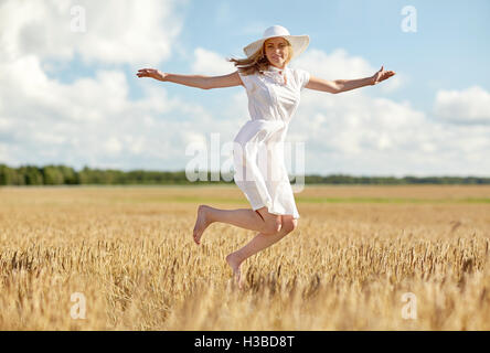 happy young woman jumping on cereal field Stock Photo