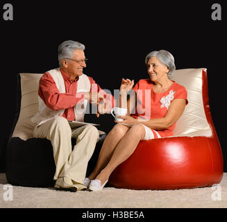 Happy senior couple sitting on armchairs Stock Photo