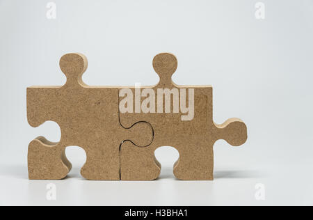 Two Wooden pieces of jigsaw puzzle with white background and selective focus Stock Photo