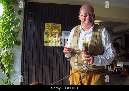 A man in lederhosen carrying a box of cigars and a glass of Riesling white wine,  Weingut Erhard Bartz, Enkirch, Mosel, Germany Stock Photo