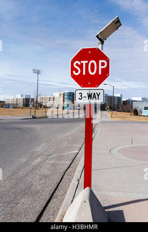 Three-way solar-powered traffic stop sign in a residential neighborhood with tiny light bulbs around the sign that light up at n Stock Photo