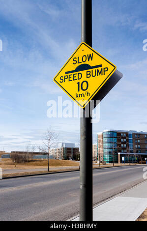 A slow down traffic sign in a residential area indicating a speed bump and a 10 km per hour driving speed. Stock Photo