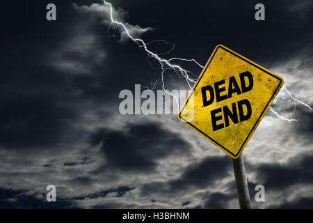 Dead end road sign against a stormy background with lightning and copy space. Dirty and angled sign adds to the drama. Stock Photo