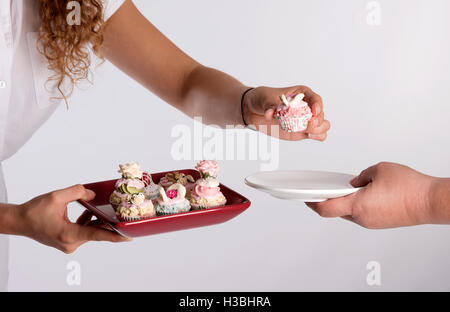 A waitress serving a tray of fairy cakes Stock Photo