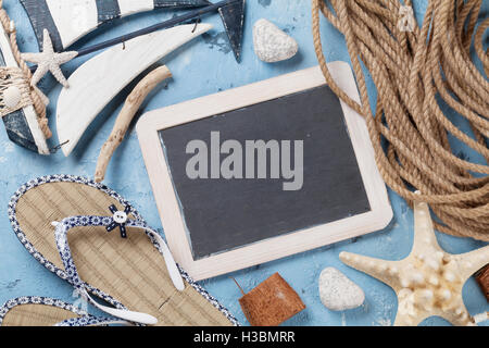 Beach accessories. Flip-flops, boat, seashells and blackboard for your text on stone background. Top view with copy space Stock Photo
