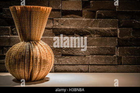 Paper vase sculpture is made from a damaged, old vintage hardcover book, brick wall background - Do It Yourself Stock Photo
