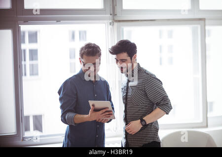 Editor showing digital tablet with colleague Stock Photo