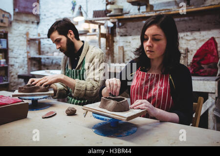 Concentrated female potter with male colleague working at table Stock Photo