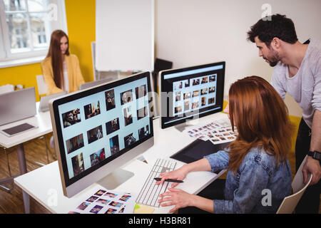 Female photo editor with coworkers working on computers Stock Photo
