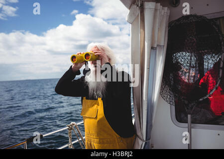 Fisherman looking through binoculars Stock Photo