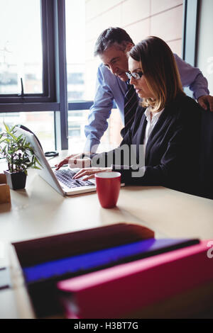 Businessman discussing with colleague over laptop Stock Photo