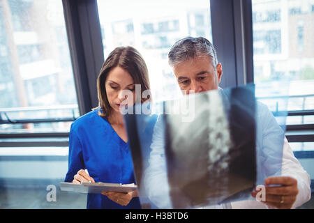 Doctor examining x-ray while nurse writing on clipboard Stock Photo