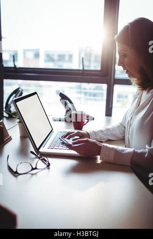 Woman holding mobile phone and using laptop Stock Photo