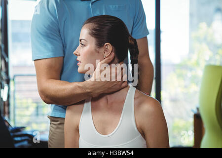 Physiotherapist examining neck of a female patient Stock Photo