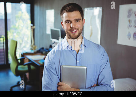 Portrait of male physiotherapist holding digital tablet Stock Photo