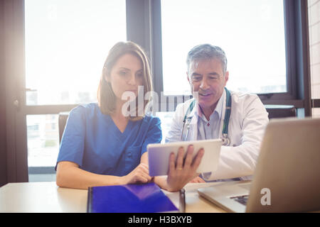 Doctor discussing with nurse over digital tablet Stock Photo