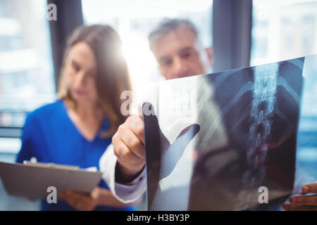Doctor examining x-ray while nurse writing on clipboard Stock Photo