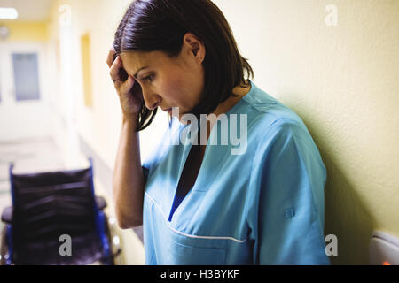 Depressed nurse standing in corridor Stock Photo