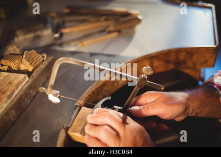 Goldsmith shaping metal with coping saw Stock Photo