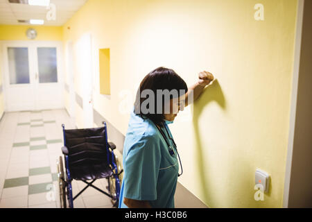 Depressed nurse standing in corridor Stock Photo