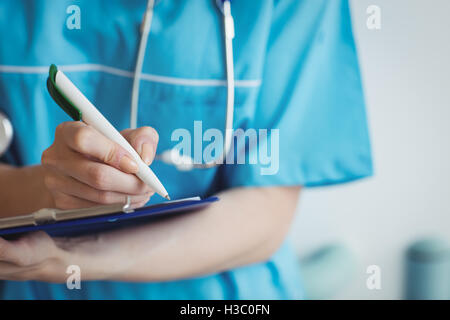 Close-up of nurse writing on clipboard Stock Photo