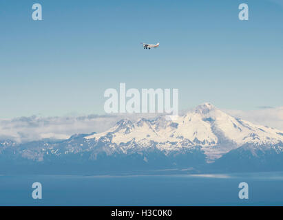 A tourist airplane flies in front of the volcano, Mt. Iliamna, over the Cook Inlet, Alaska. Stock Photo