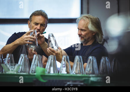 Glassblower and a colleague examining glassware Stock Photo