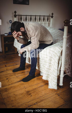 Depressed man sitting on bed Stock Photo