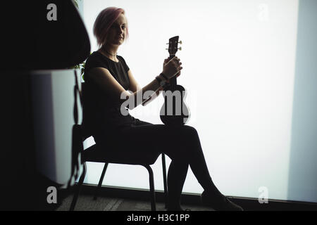 Woman sitting with a guitar in music school Stock Photo
