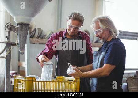 Glassblower and a colleague looking glassware Stock Photo