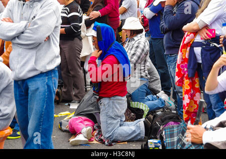 QUITO, ECUADOR - JULY 7, 2015: People on knees in the middle of the mass, praying. Family on the floor Stock Photo
