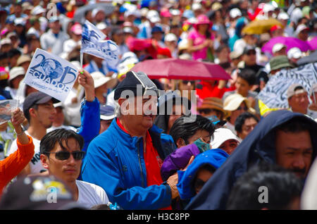 QUITO, ECUADOR - JULY 7, 2015: In the middle of thousand people, a big man with blue pull is praying, holding a jacket Stock Photo