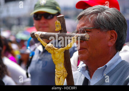 QUITO, ECUADOR - JULY 7, 2015: Old man holding a big cross with jesus body representation, pope Francisco mass with lots of people Stock Photo