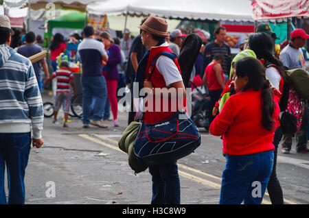 QUITO, ECUADOR - JULY 7, 2015: Unidentified men with hat and a big backpack watching someone in the multitude Stock Photo