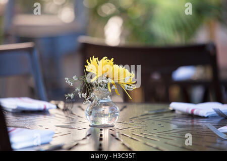 Table setting at a restaurant patio with yellow flower in a vase Stock Photo
