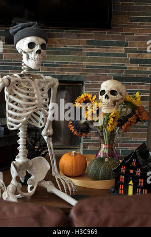 Halloween skeleton sitting on a sofa and showing his holiday decor Stock Photo