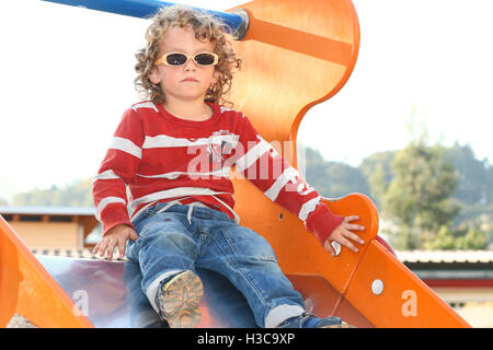 Blonde curly haired child with sunglasses playing at the playground Stock Photo