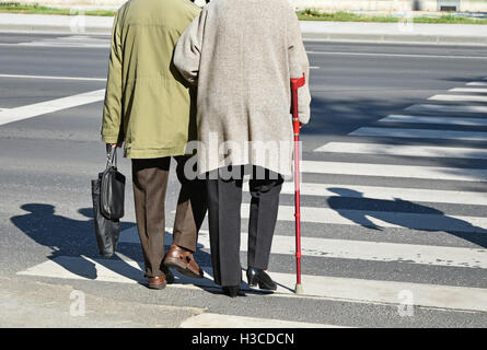 Old couple walks on the pedestrian crossing Stock Photo