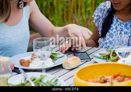 Women looking at smartphone while dining together outdoors Stock Photo