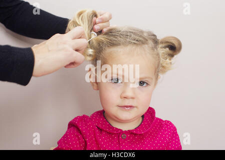 Little girl having her hair arranged in pigtails Stock Photo