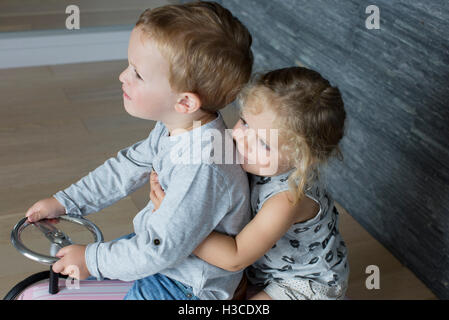 Children riding together on toy car Stock Photo