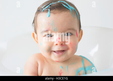 Baby splattered in colorful soap at bathtime Stock Photo