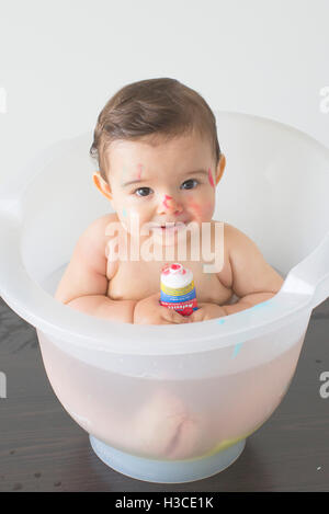 Baby sitting in bath with tube of colorful soap Stock Photo